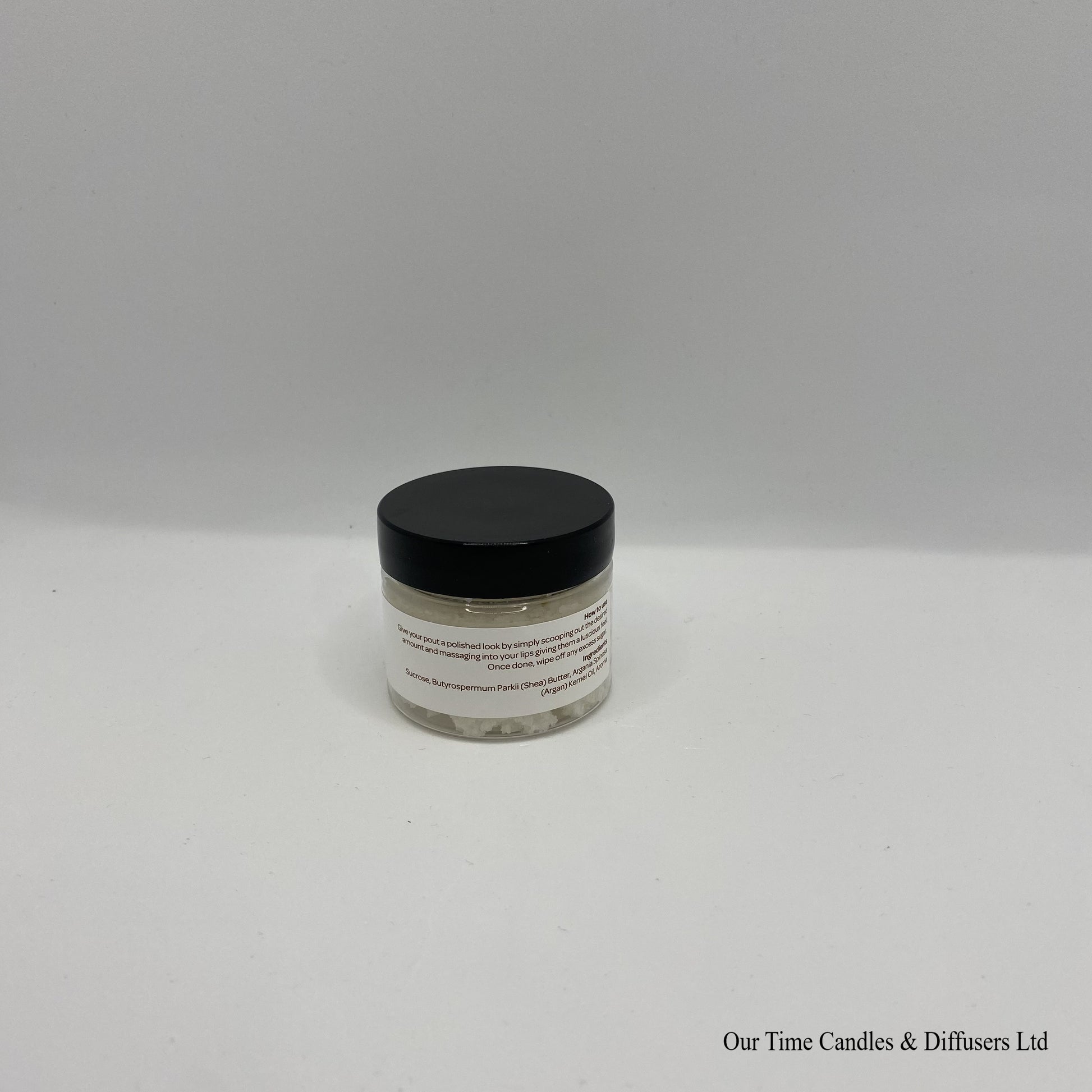 Small clear jar containing lip scrub with black lid