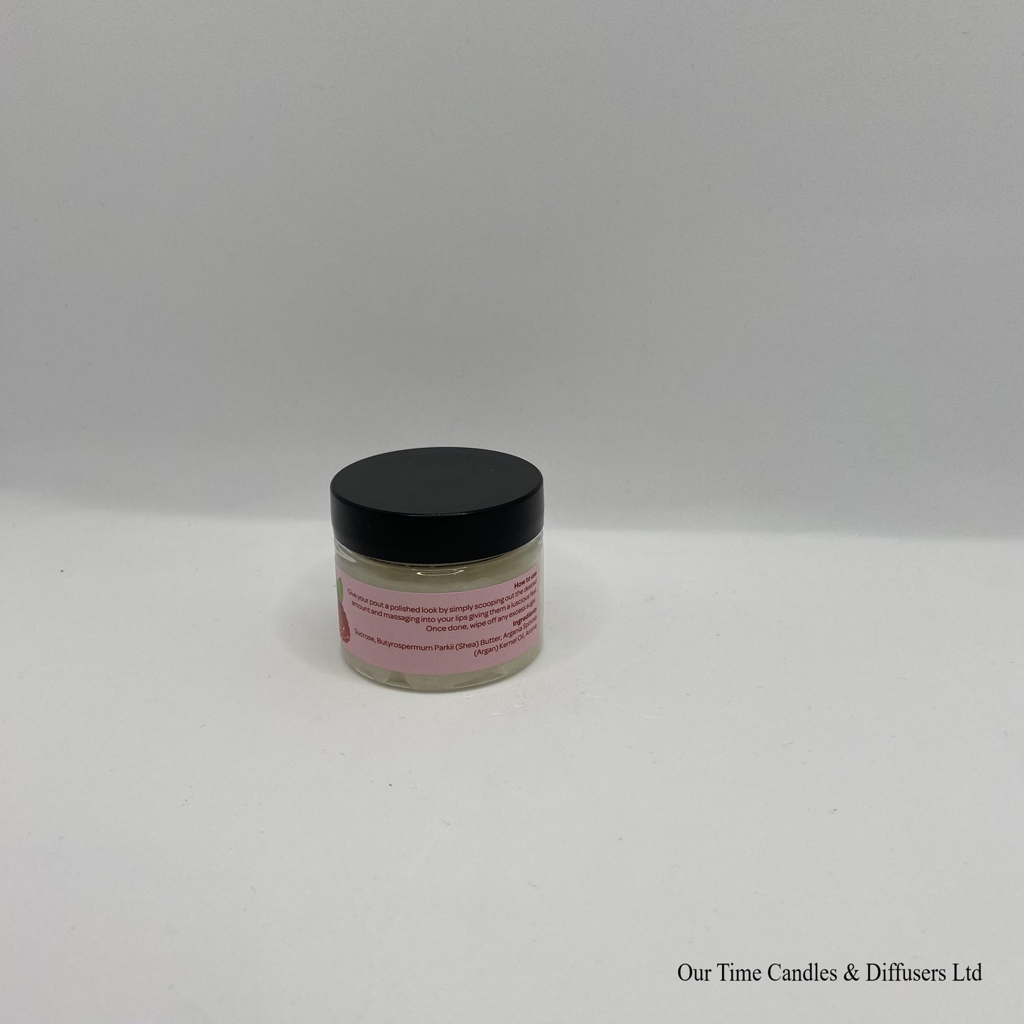 Small clear jar containing lip scrub with black lid