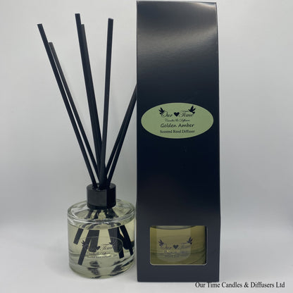 Reed Diffuser in black box sat next to reed diffuser in use, clear bottle with black reeds.