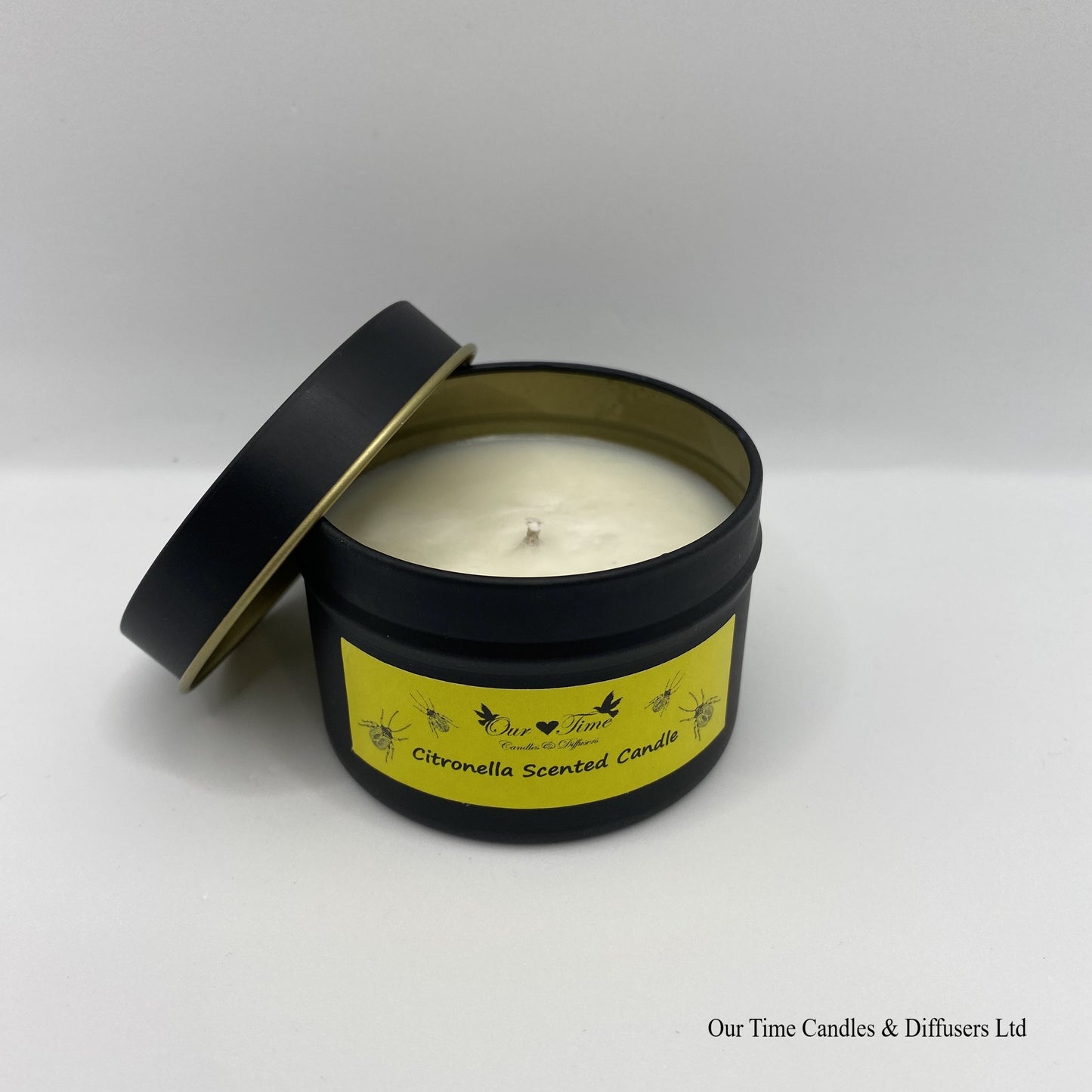 Citronella scented candle in a black tin with yellow label with lid off