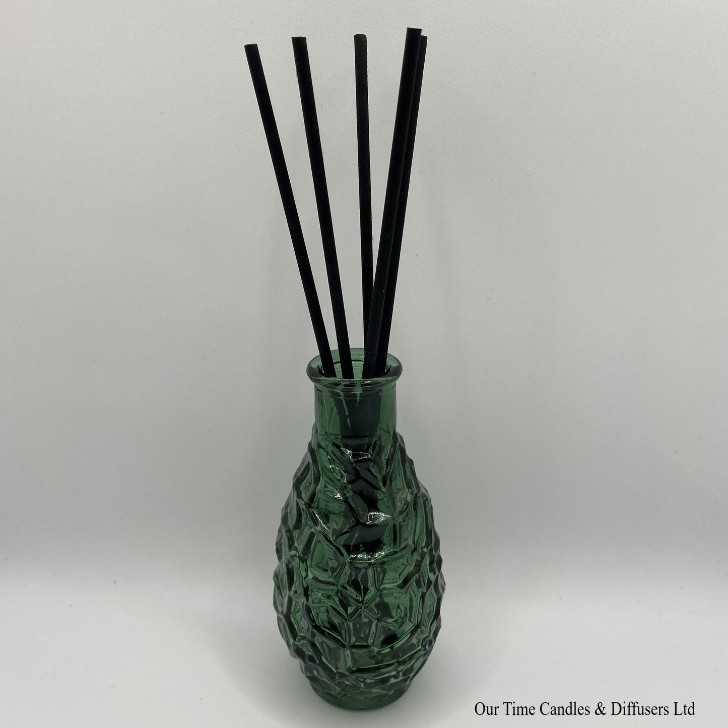 Decorative diffuser vase in green shown with reeds
